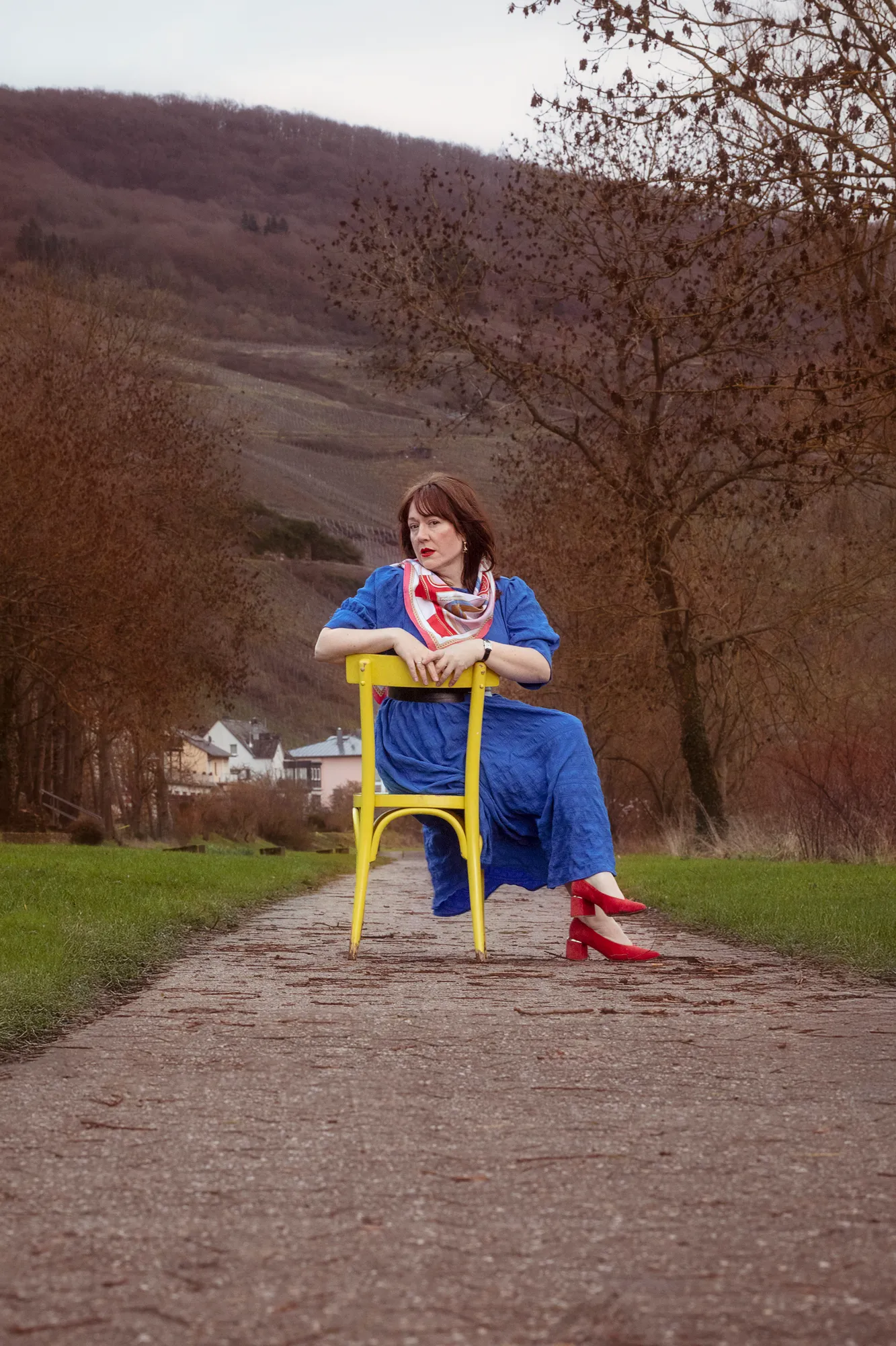 Editorial portrait on a yellow chair on a vineyard path