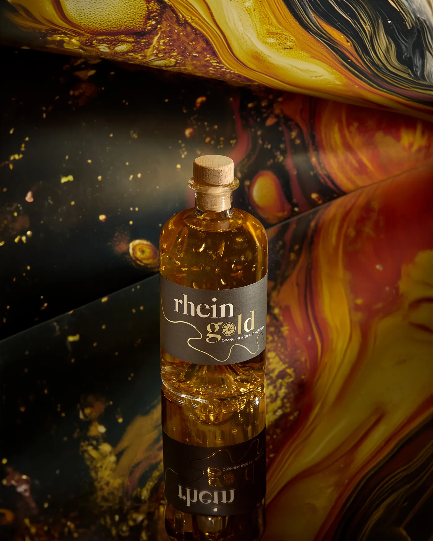 Rheingold orange liqueur bottle with gold flakes suspended in it, against marbled gold and red